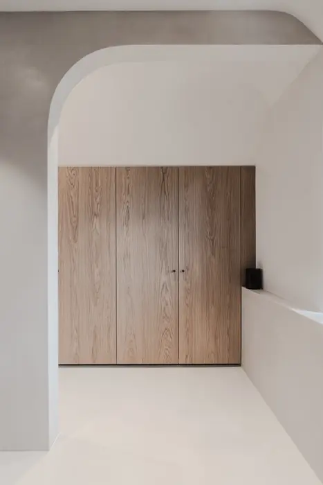 Strakke wandopbouw met boogdetail en houten deur